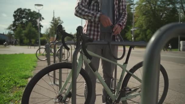 Ασφάλεια Και Αντικλεπτική Κλειδαριά Για Ποδήλατο Αρσενικός Ποδηλάτης Κλειδώνει Ποδήλατο — Αρχείο Βίντεο