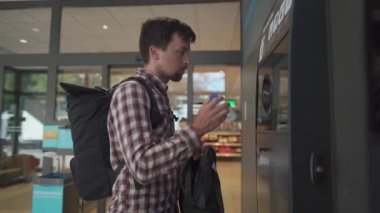 Adam, para karşılığında otomatik makine koleksiyoncusunda plastik şişeyi geri dönüştürüyor. Plastik şişe geri dönüşüm makinesi. Ekoloji konsepti. Geri dönüşüm. Plastik şişelerin iadesi ve geri dönüşümü. Dönüş noktası. 