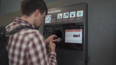 Adam, para karşılığında otomatik makine koleksiyoncusunda plastik şişeyi geri dönüştürüyor. Plastik şişe geri dönüşüm makinesi. Ekoloji konsepti. Geri dönüşüm. Plastik şişelerin iadesi ve geri dönüşümü. Dönüş noktası 