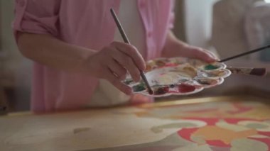 Parlak sanat stüdyosundaki kadın ressamın tuvale fırça ve yağlı boyalarla yaptığı yakın çekim. Sanat okulu ya da stüdyo. Boyalarla, fırçalarla ve sehpalarla çalışıyorum. İlham, yaratıcılık, yetenek, konsept