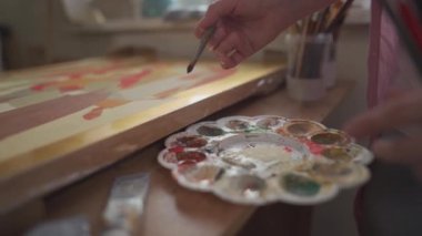 Parlak sanat stüdyosundaki kadın ressamın tuvale fırça ve yağlı boyalarla yaptığı yakın çekim. Sanat okulu ya da stüdyo. Boyalarla, fırçalarla ve sehpalarla çalışıyorum. İlham, yaratıcılık, yetenek, konsept