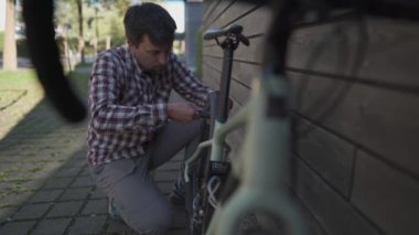 Adam Almanya 'da bir bisiklet parkında lastiği küçük el pompasıyla şişiriyor. Konu amatör bisiklet bakım, onarım ve ayarlama. Bir bisikletçi Gerevel motosikletinin lastiğini şişiriyor.. 
