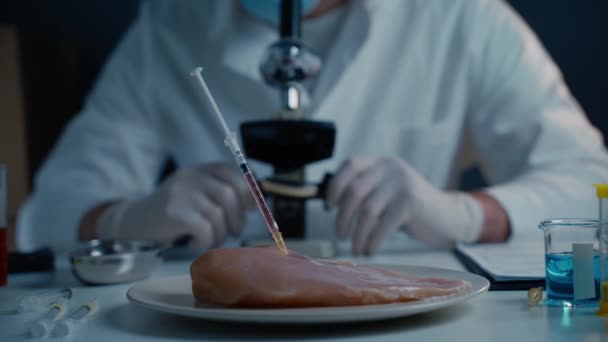 ラボアシスタントテストGmoチキン 食品品質管理担当者が顕微鏡の裏側のサンプルを調べます 食物中の抗生物質の残留物を遺伝的に修飾した 食料技術だ 食品品質管理コンセプト — ストック動画