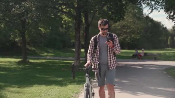 Ένα Αρσενικό Περπατάει Δίπλα Στο Ποδήλατό Του Και Χρησιμοποιεί Ένα — Αρχείο Βίντεο