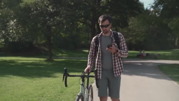 Мужчина Велосипедист Гуляет Велосипеде Парку Пользуется Смартфоном Солнечную Погоду Германии — стоковое видео