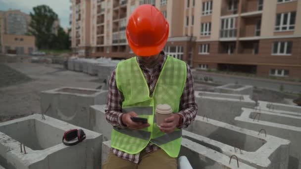 Robotnik Budowlany Odpoczywający Placu Budowy Pijący Kawę Korzystający Smartfona Siedząc — Wideo stockowe