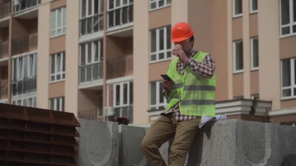 Stavitel Odpočívá Stavebních Prvcích Pracovišti Pije Kávu Surfuje Internetu Smartphonu — Stock video