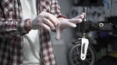 Bisiklet tamircisi bisiklet dükkanında koruyucu beyaz lastik eldiven giyer. Bisiklet tamircisi atölyede lateks eldiven giyer. Servis teknisyeni iş eldiveni takar. Görevli koruyucu eldiven takıyor.. 