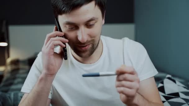 Mężczyzna Trzyma Test Ciążowy Radością Dzwoni Przyjaciela Przekazać Dobre Wieści — Wideo stockowe