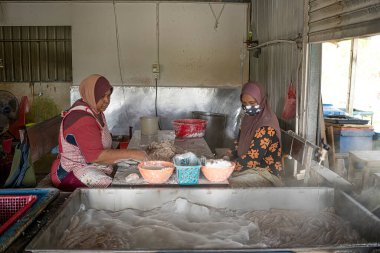 Terengganu, Malezya: 16 Ocak 2022 - Ünlü keropok lekor veya balık sosisi yapan iki kadın