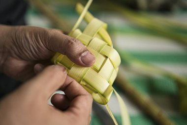 Hindistan cevizi yapraklarını dokumak, bayram kutlamalarında geleneksel Malezya mutfağı olan ketupatı yapmak. Seçici odak noktaları
