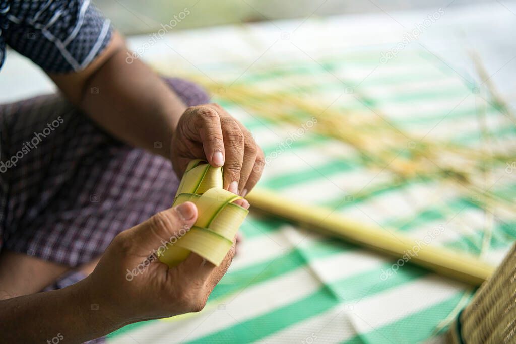 Weaving the coconut leaves making the ketupat, a traditional Malay cuisine during the Eid celebration. Selective focus points