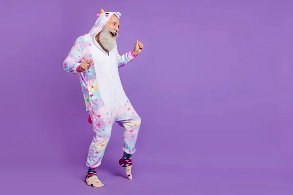 Full body photo of happy positive old man wear pajama dance look empty space isolated on purple color background — Stock Photo, Image