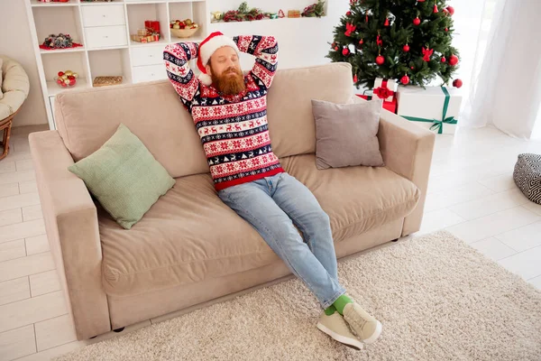 Helkroppsfoto av ung man glad positiv leende vila slappna av händerna bakom huvudet jul atmosfär inomhus — Stockfoto