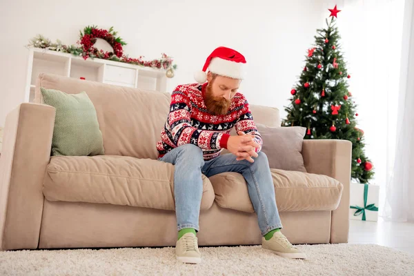 Full length photo of young man sit couch comfort cozy moody think christmas atmosphere tree noel indoors — Stock Photo, Image