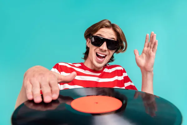 Porträtt av attraktiva funky glad DJ kille spelar vinyl skiva isolerad över ljusa teal turkos färg bakgrund — Stockfoto