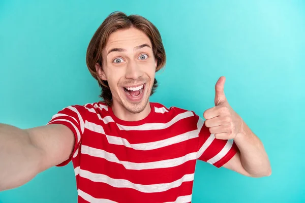 Фото молодого парня счастливая положительная улыбка запись видео показывают большой палец вверх, как штраф обратной связи рекламы изолированы на бирюзовом фоне цвета — стоковое фото