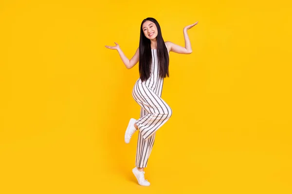 Longitud completa tamaño del cuerpo foto chica sonriendo en general rayas hombros encogiéndose de hombros inseguro aislado vibrante color amarillo fondo — Foto de Stock