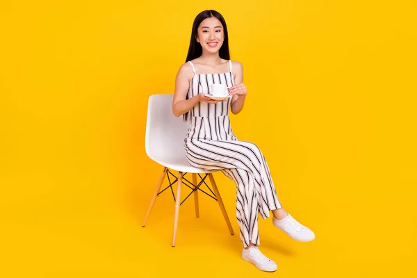 Volledige lengte lichaam grootte foto meisje glimlachen gelukkig in gestreepte totale drinken thee geïsoleerde levendige gele kleur achtergrond — Stockfoto