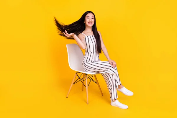 Longitud completa tamaño del cuerpo foto joven sentada en la silla con casual general sonriente arrojar pelo aislado vívido color amarillo fondo — Foto de Stock