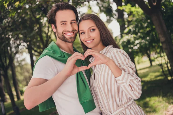 Photo portrait couple spending time in park happy showing heart sign gesture with hands together — Stock Photo, Image