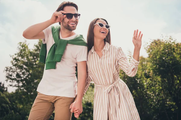 Foto portriat jovem casal sorrindo no verão indo no parque rindo feliz acenando as mãos — Fotografia de Stock