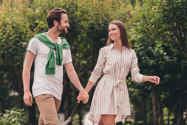 Foto portriat junges Paar lächelnd zu Fuß im grünen Park Händchen haltend bei einem Date mit guter Laune — Stockfoto