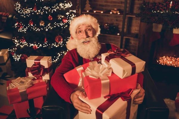 Foto de sênior santa claus feliz sorriso positivo sentar poltrona segurar presente caixa novo ano atmosfera luzes milagre dentro de casa — Fotografia de Stock