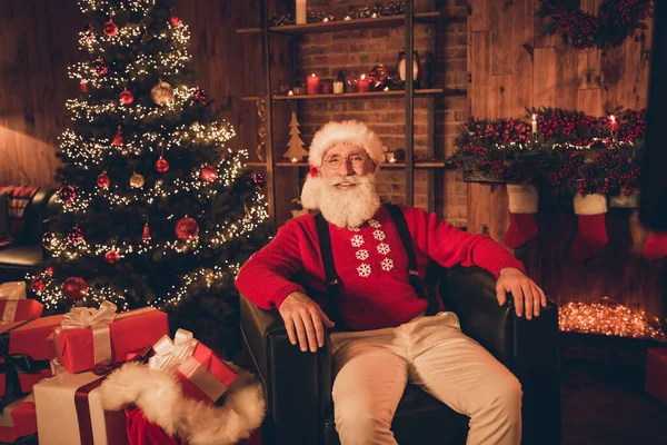 Photo de père Noël claus heureux sourire positif assis chaise pôle nord repos relax décoration Noël temps intérieur — Photo