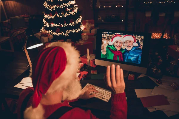 Foto von süßen ziemlich reifen Mann gekleidet Weihnachtsmann Kostüm sprechen modernes Gerät winkt Arm in Innenräumen Home Room — Stockfoto