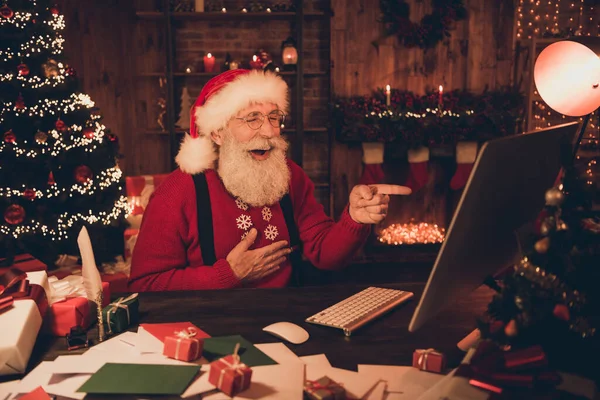 Foto van grappige kerstman kijken pc scherm directe vinger lachen grap dragen hoed trui in noordpool kantoor binnen — Stockfoto