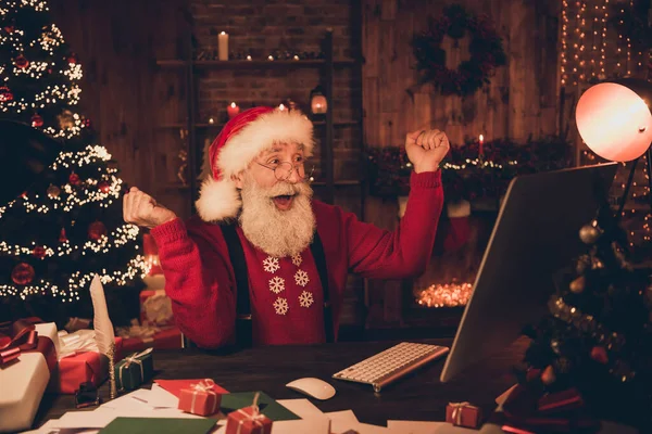 Foto der erstaunten Weihnachtsmann Blick PC-Bildschirm heben Fäuste tragen Hut Pullover in Nordpol-Büro drinnen — Stockfoto