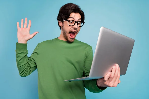 Retrato de joven emocionado loco alegre chico en gafas gritar en triunfo victoria utilizando portátil aislado sobre fondo de color azul — Foto de Stock