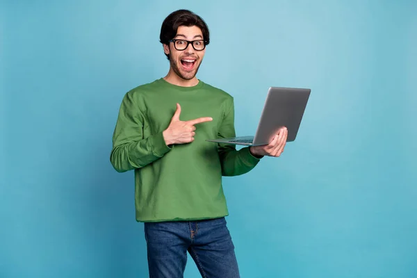 Foto de sorprendido sorprendido hombre positivo punto dedo portátil usar gafas aisladas sobre fondo de color azul pastel — Foto de Stock