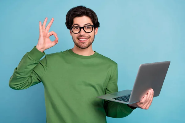 Портрет усміхненого ботаніка молодого бізнесмена в окулярах показують добре знак тримає ноутбук ізольований на синьому кольорі — стокове фото