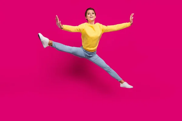 Фото забавной очаровательной юной леди носить желтый свитер улыбаясь прыжки высокие стороны рук изолированный розовый цвет фона — стоковое фото