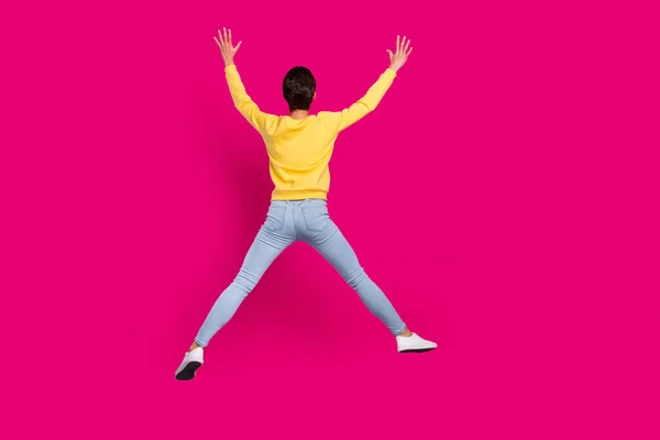 Foto de divertida joven funky usar jersey amarillo sonriendo saltando alto como la estrella aislado color rosa fondo —  Fotos de Stock