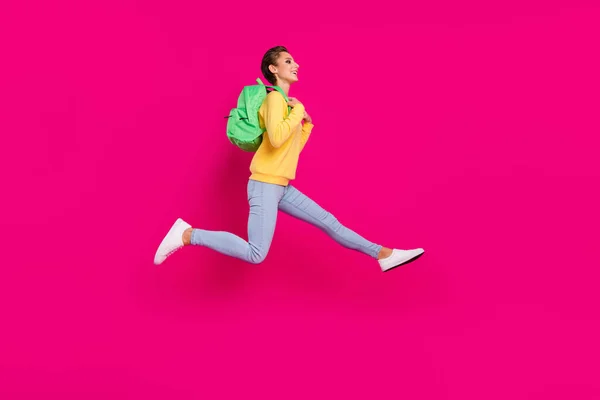 Foto de brillante encantadora joven dama usar amarillo jersey mochila saltar corriendo buscando espacio vacío aislado color rosa fondo —  Fotos de Stock
