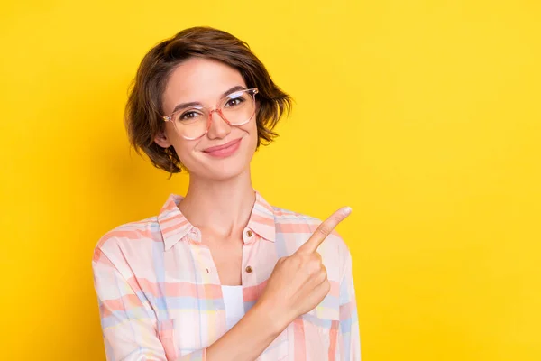 Foto de alegre jovem feliz mulher apontar dedo notícias espaço vazio usar óculos isolados no fundo de cor amarela — Fotografia de Stock