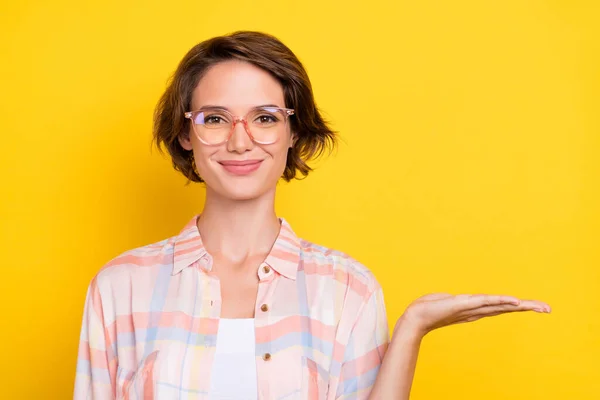 幸せな正の素敵な女性のホールド手空のスペースオブジェクトは、黄色の色の背景に隔離されたメガネを着用 — ストック写真
