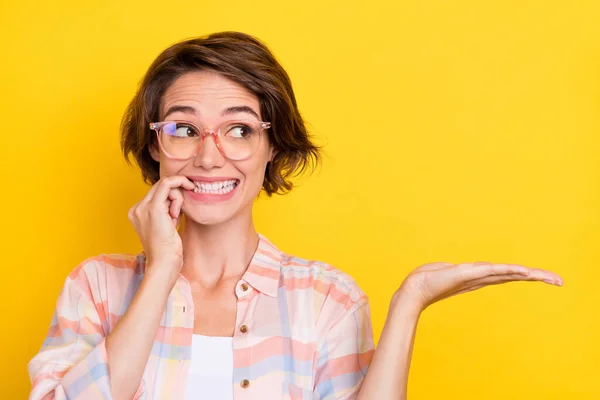 Zdjęcie nieszczęśliwej młodej kobiety trzymać za rękę pusty obiekt przestrzeni nosić okulary izolowane na żółtym tle koloru — Zdjęcie stockowe