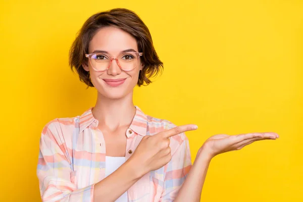 Foto van vrolijke gelukkig mooie jonge vrouw houden hand leeg punt vinger raden geïsoleerd op gele kleur achtergrond — Stockfoto