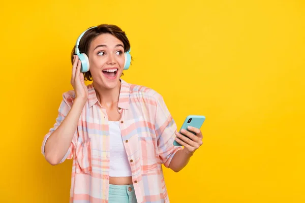 Portret van aantrekkelijke vrolijke meisje luisteren hit lied melodie met behulp van apparaat kopiëren ruimte geïsoleerd over helder gele kleur achtergrond — Stockfoto