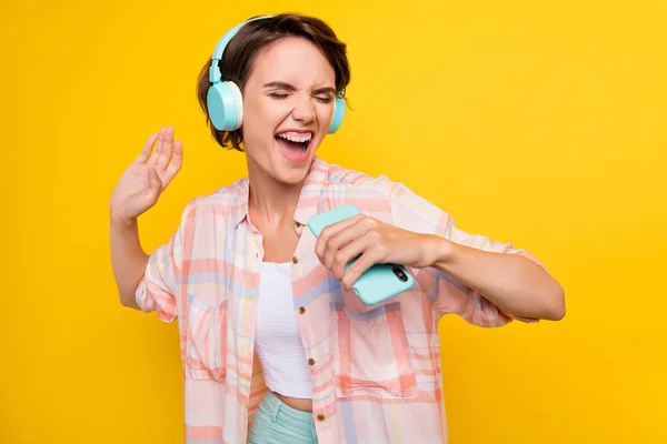 Canlı sarı arka planda izole edilmiş bir cihaz kullanarak hit şarkılar dinleyen çekici kızın portresi — Stok fotoğraf