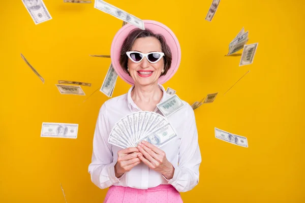 Foto von reifen Geschäftsfrau glücklich positives Lächeln Luft fliegen Geld Dollar wohlhabend isoliert über gelben Farbhintergrund — Stockfoto