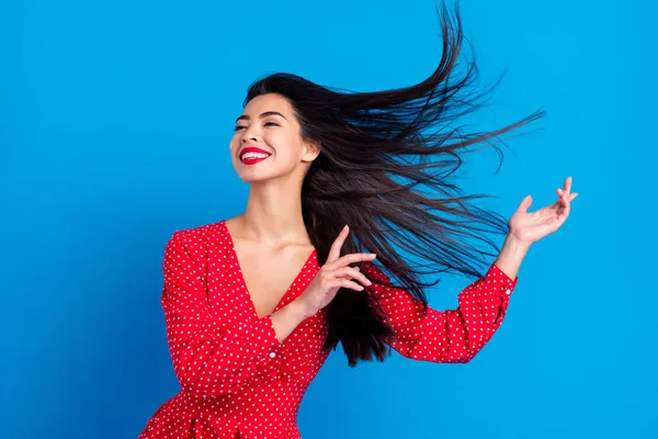 Foto retrato de mujer sonriente bailando en vestido rojo con el pelo volador aislado sobre fondo de color azul vivo —  Fotos de Stock