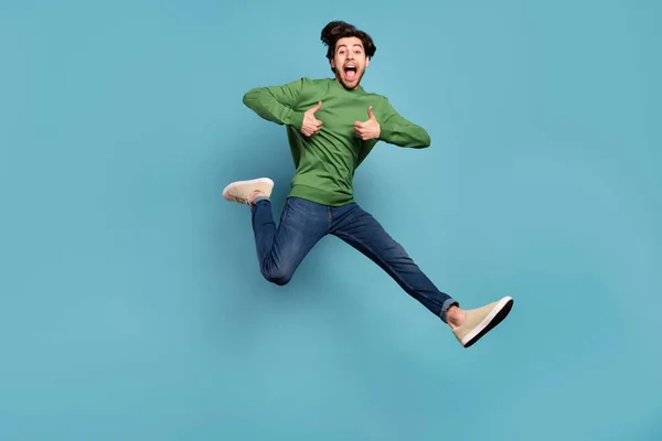 In voller Länge Foto der Brünette erstaunt glücklich Mann springen machen Daumen nach oben laufen Verkauf tragen Jeans isoliert auf blauem Hintergrund — Stockfoto