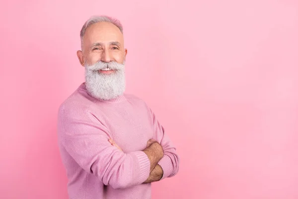 Foto de perfil de alegre pelo gris envejecido hombre cruzó los brazos cerca del espacio vacío desgaste suéter rosa aislado sobre fondo pastel — Foto de Stock