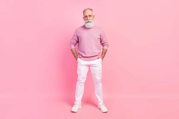 Фото серьезного уверенного возраста джентльмен носить свитер очки стоя руки карманы изолированные розовый цвет фона — стоковое фото