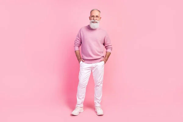 Foto van zelfverzekerde mooie leeftijd heer dragen trui bril staande armen zakken glimlachen geïsoleerde roze kleur achtergrond — Stockfoto